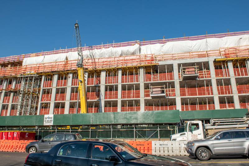 Construction worker in a high-visibility vest and hard hat, operating or working near machinery.